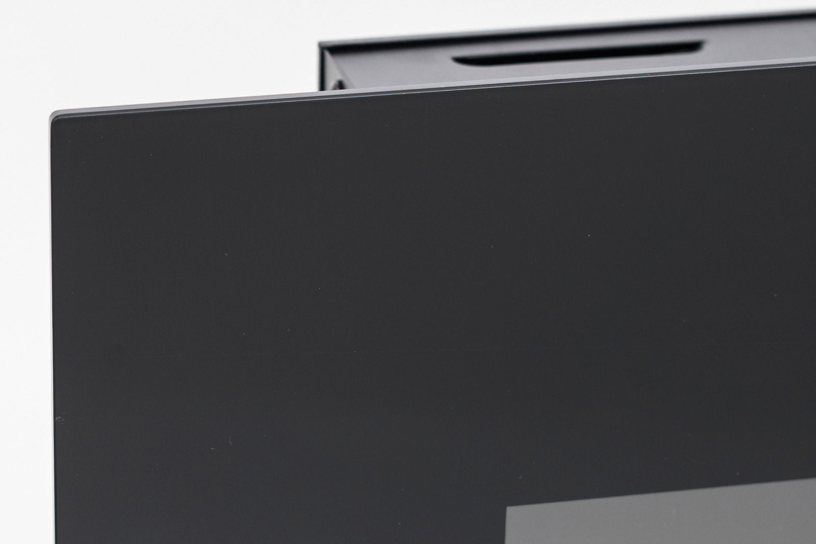 Nahaufnahme einer Ecke eines schwarzen Elektrokamins mit glatter Oberfläche, seitliche Perspektive.