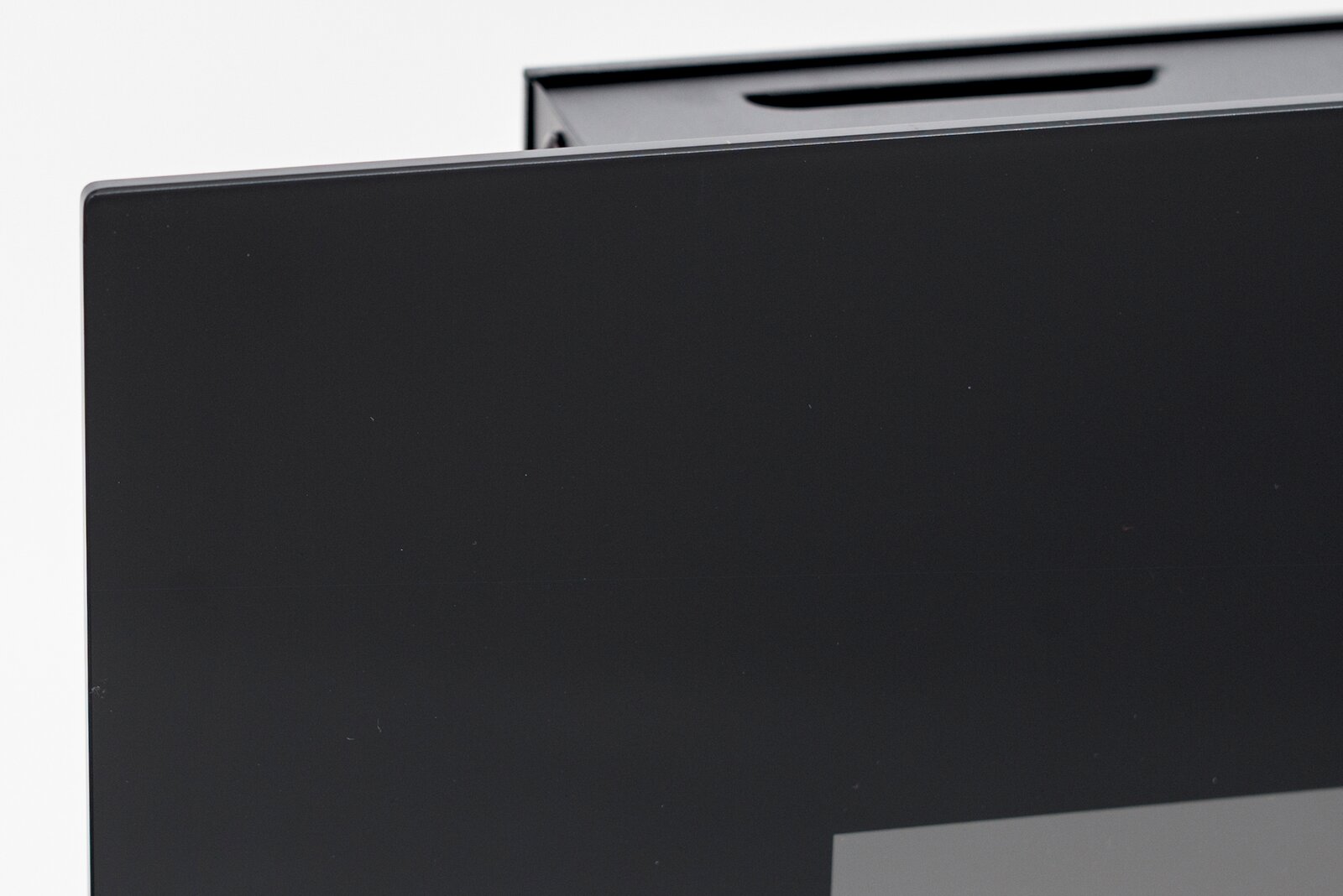 Nahaufnahme einer Ecke eines schwarzen Elektrokamins mit glatter Oberfläche, seitliche Perspektive.