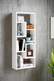 Weißes, modernes Wandregal mit asymmetrischen Fächern an einer grauen Betonwand, dekoriert mit Büchern, Glasgefäß, kleiner Pflanze, Uhr und orangefarbener Vase; perspektivische Frontansicht leicht von links.