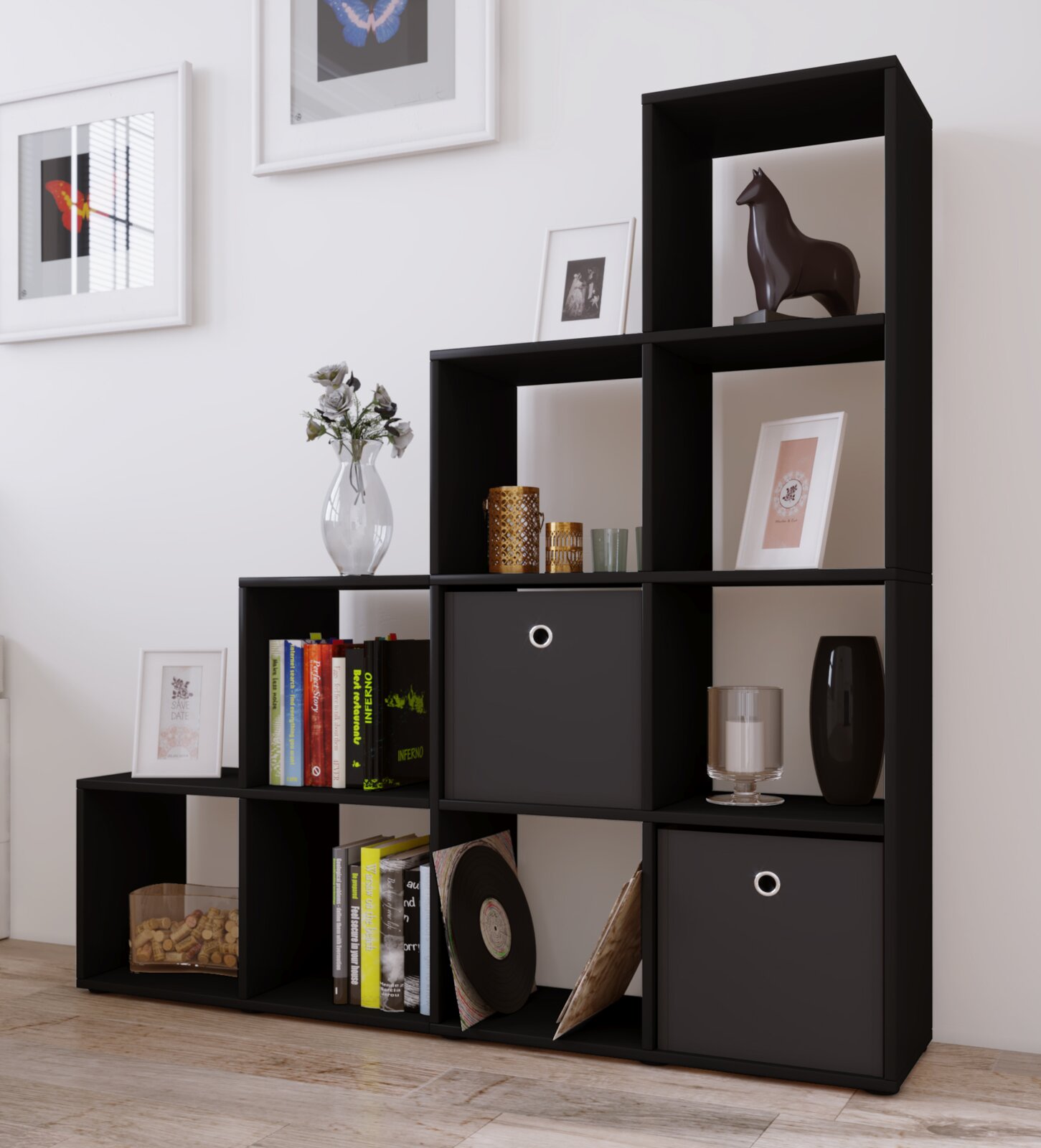 Modernes schwarzes Würfel-Regalsystem mit offenen Fächern und zwei Schubladen, dekoriert mit Büchern, Bilderrahmen, Vase und Kerzen, aufgenommen in leichter Schrägansicht von vorn (Wohnraum-Setting).