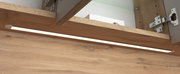 Nahaufnahme eines Spiegelschranks mit Holzoptik und integrierter LED-Beleuchtung von unten betrachtet.