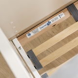 Nahaufnahme eines Babybettgestells mit Holzlatten und Sicherheitszertifikat, von oben betrachtet.