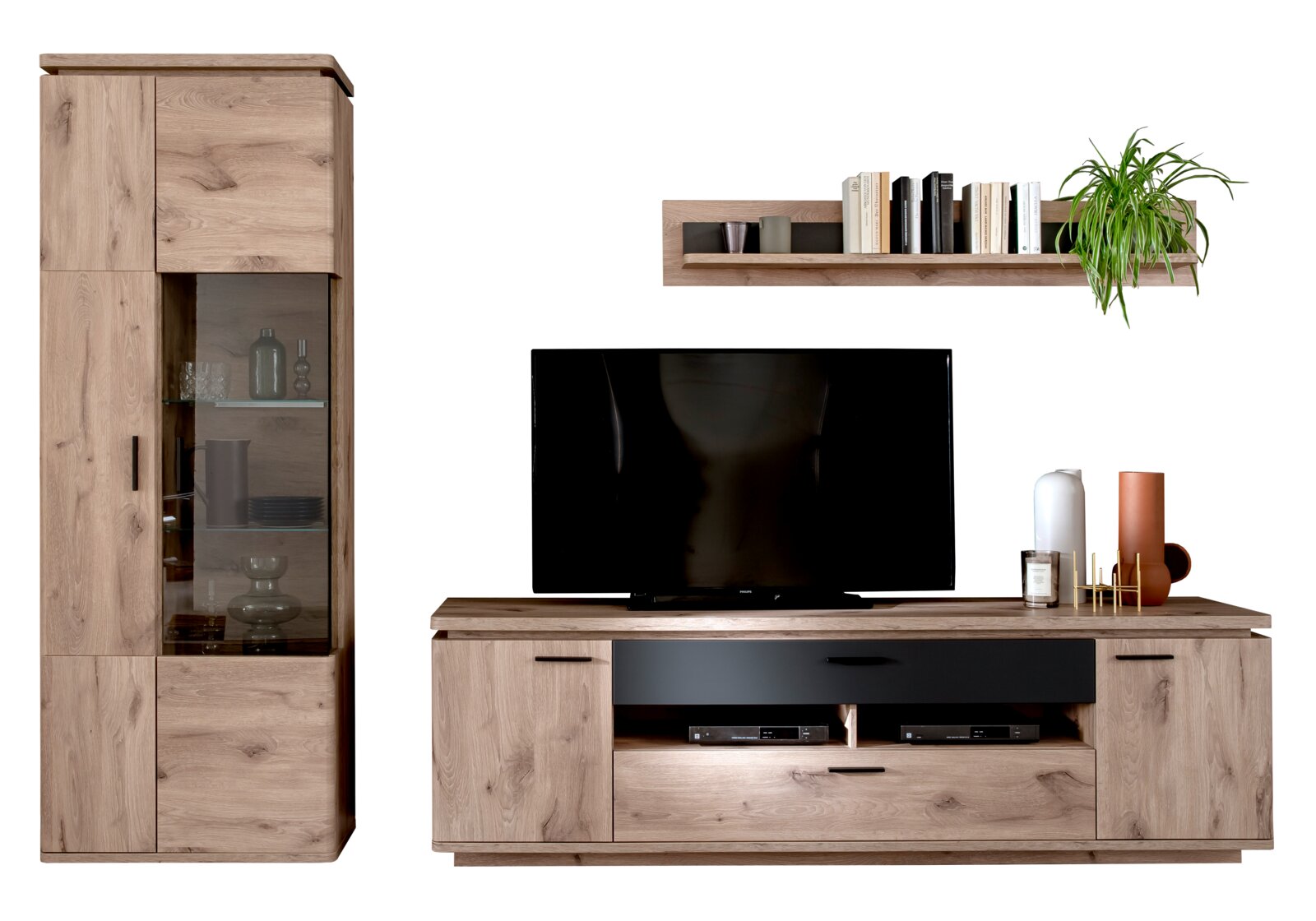 Wohnwand im Eiche-Optik-Design mit hoher Vitrine mit Glastür, TV-Lowboard mit schwarzen Fronten und Wandregal mit Büchern und Pflanze, frontal aus leicht erhöhter Perspektive