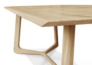 Nahaufnahme eines modernen Esstisches aus Holz mit abgeschrägter Tischkante und einzigartigem Tischbein-Design, seitliche Perspektive.