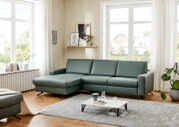 Grüne Longchairkombination in einem modernen Wohnzimmer mit großen Fenstern, Holzboden und minimalistischer Dekoration. Perspektive von vorne links.