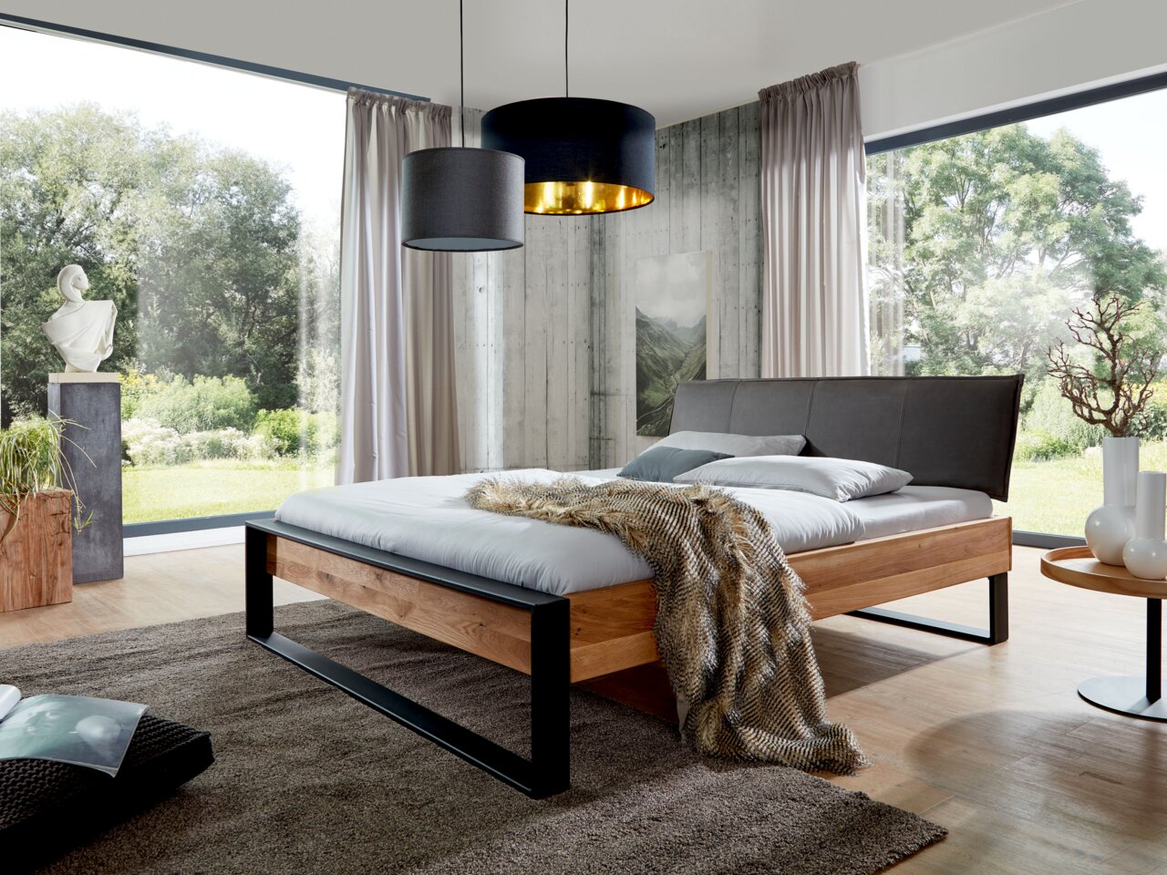 Modernes Balkenbett aus Holz mit schwarzem Metallrahmen, seitliche Perspektive, in einem hellen Raum mit großen Fenstern und stilvoller Dekoration.
