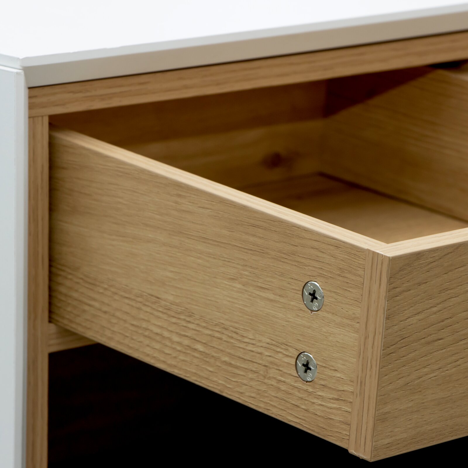 Nahaufnahme einer geöffneten Schublade eines Büroschranks aus Holz mit sichtbaren Schrauben, Perspektive von schräg oben.
