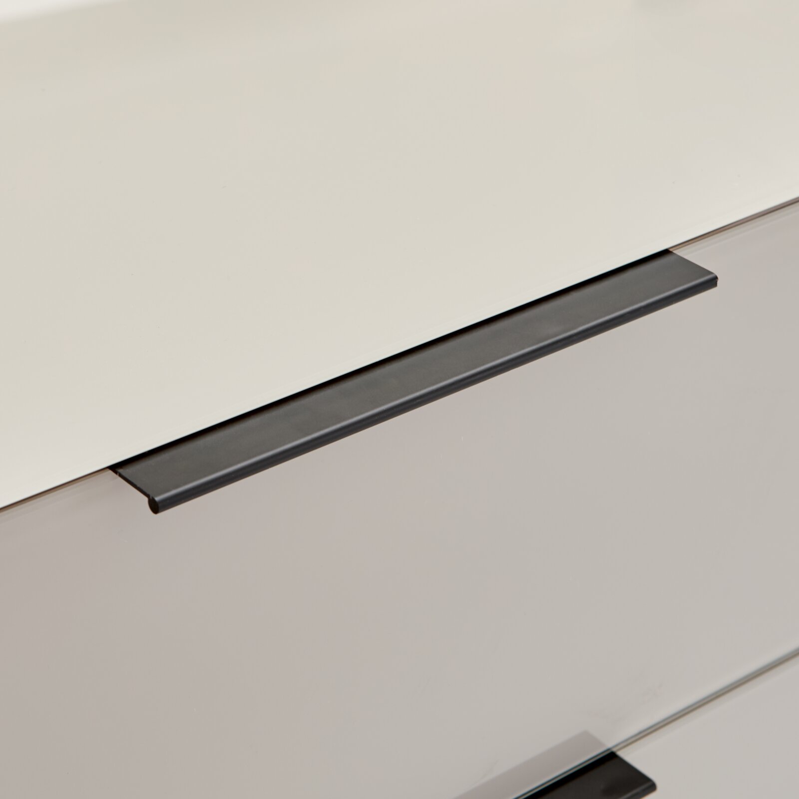Nahaufnahme in schräger Perspektive von einer Glasplatte mit schwarzer Metallkante/Profil auf hellem Hintergrund