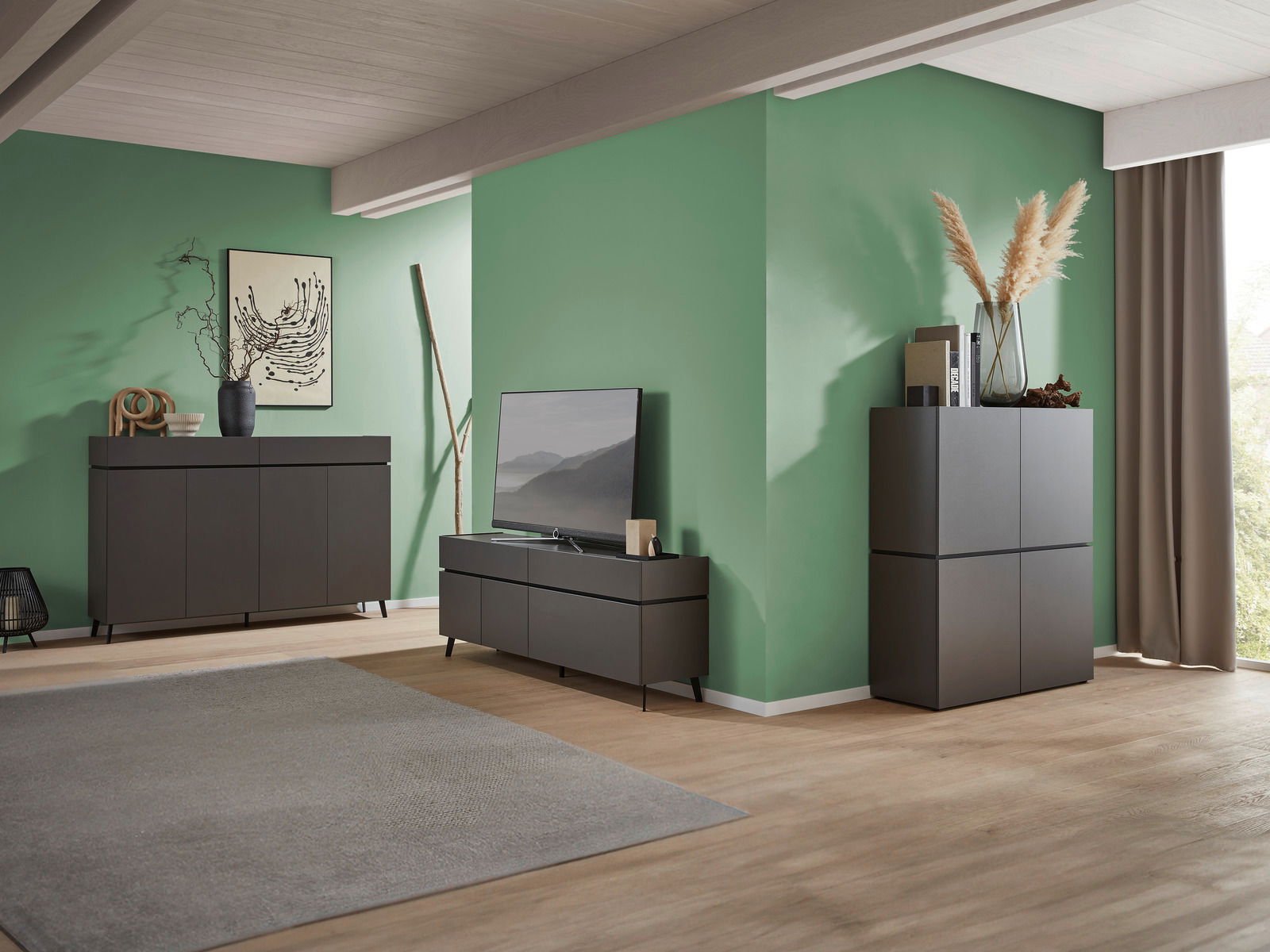 Modernes Wohnzimmer mit einem TV-Lowboard, einem Sideboard und einem Highboard in dunklem Holzdesign, seitliche Perspektive.