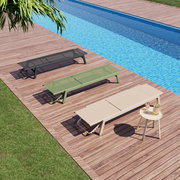 Drei Sonnenliegen in verschiedenen Farben auf einer Holzterrasse neben einem Pool, aus der Vogelperspektive fotografiert.