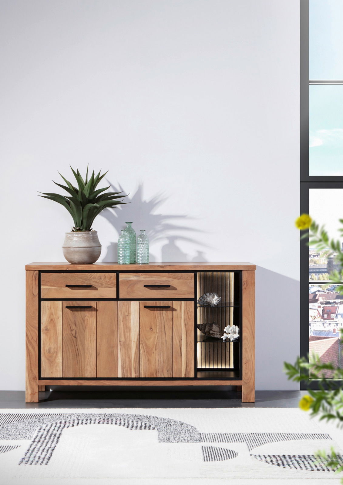 Holz-Sideboard mit zwei Schubladen und offenen Regalfächern, dekoriert mit Pflanzen und Flaschen, aus frontaler Perspektive.