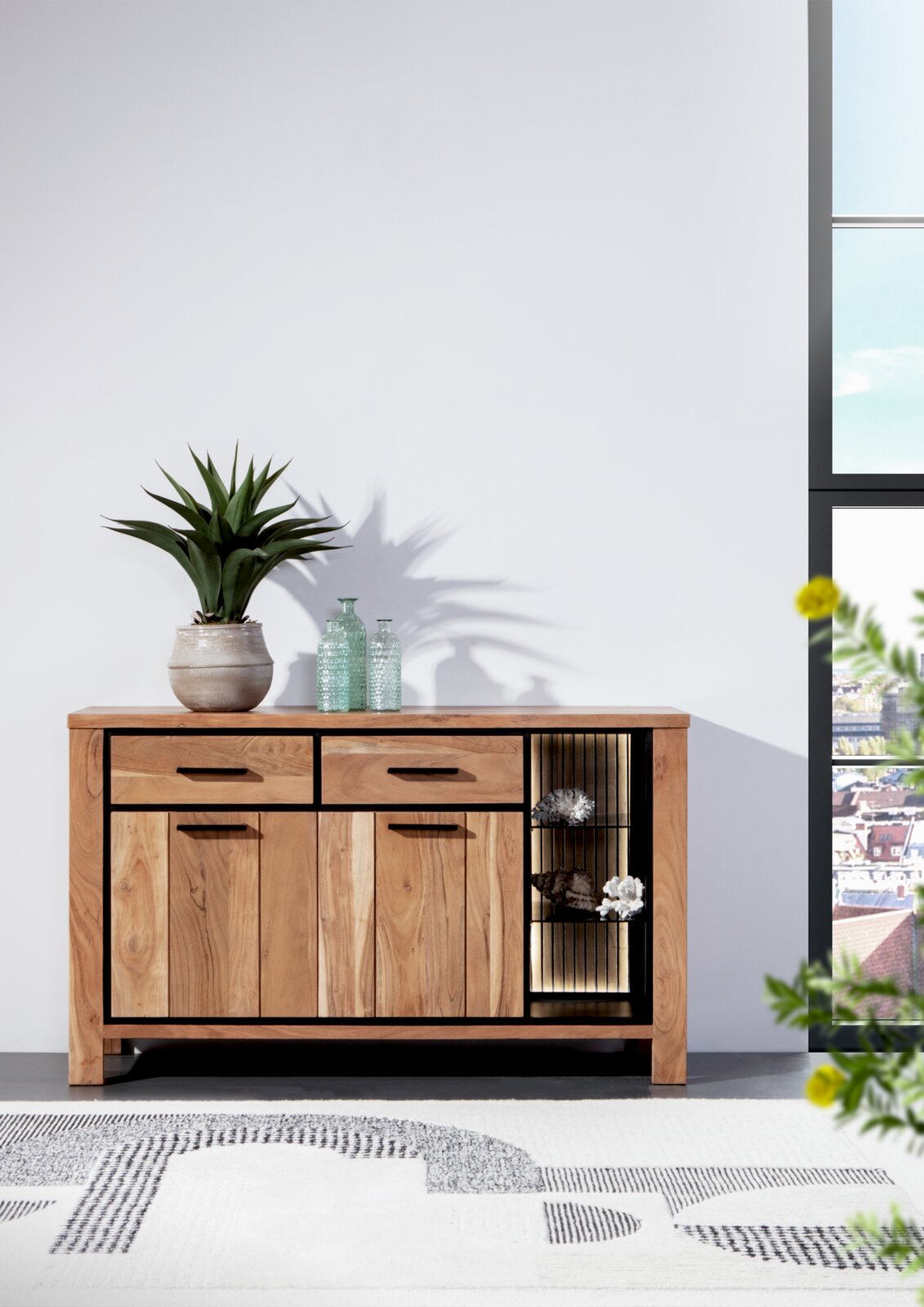 Holz-Sideboard mit zwei Schubladen und offenen Regalfächern, dekoriert mit Pflanzen und Flaschen, aus frontaler Perspektive.