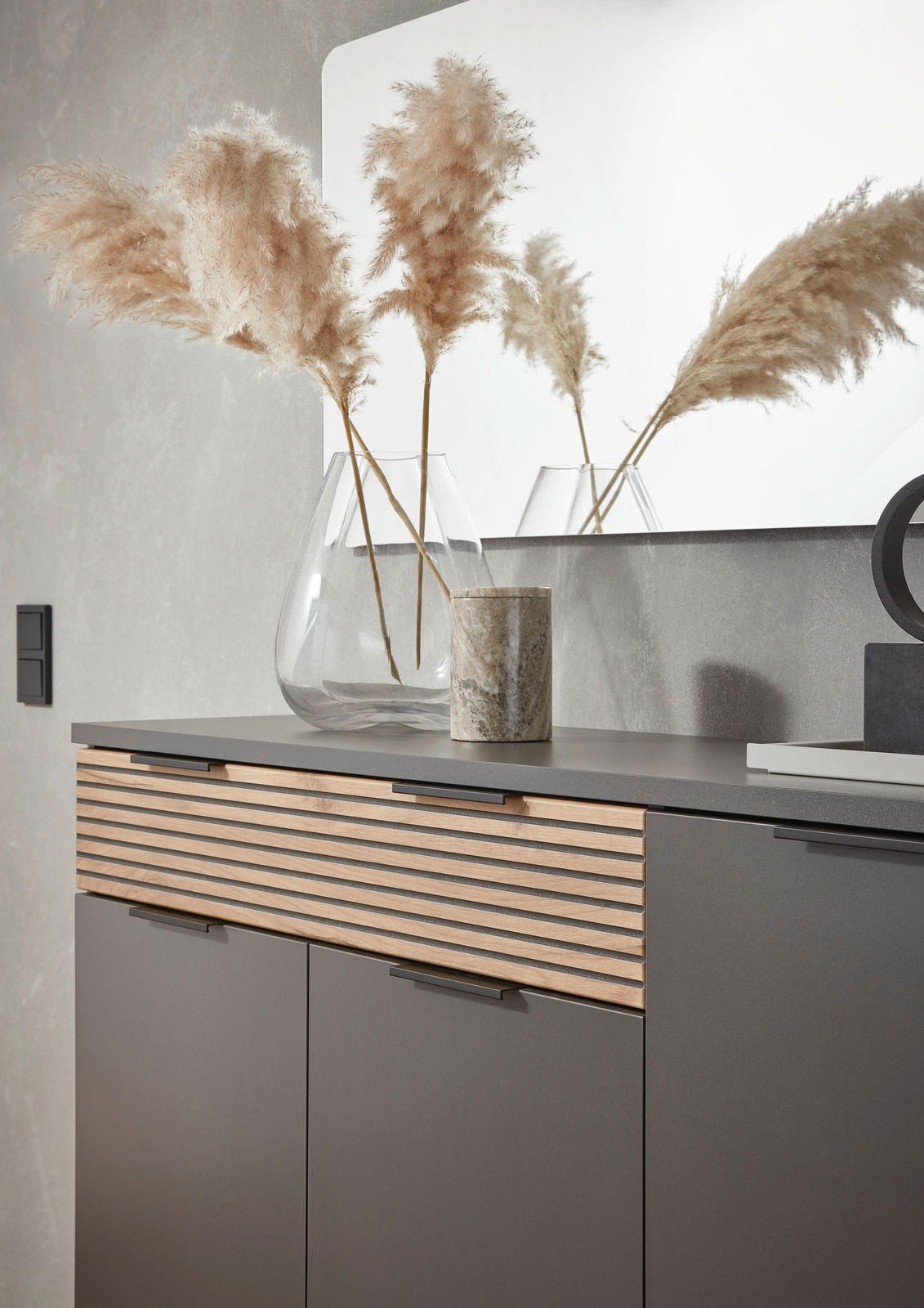 Moderner Schuhschrank mit Holzlamellen-Design, dekoriert mit einer Glasvase und Pampasgras, seitliche Perspektive