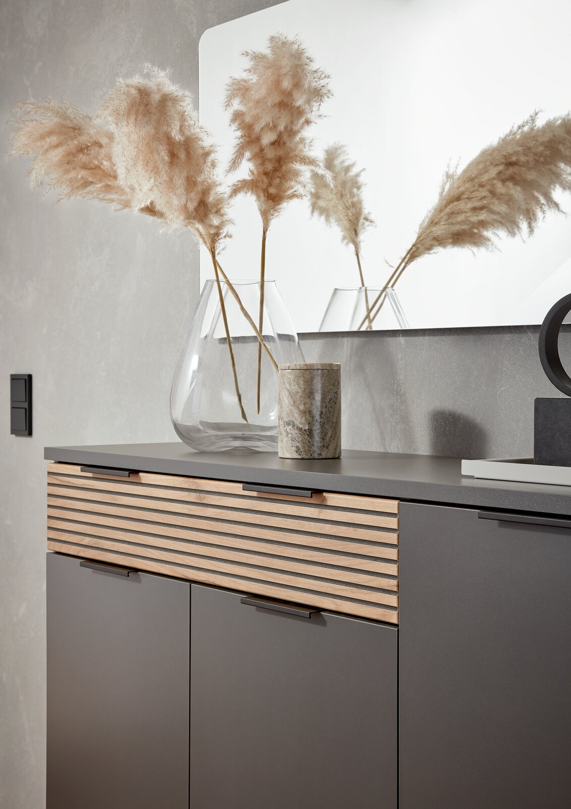 Moderner Schuhschrank mit Holzlamellen-Design, dekoriert mit einer Glasvase und Pampasgras, seitliche Perspektive