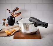 Schnellkochtopf WMF Perfect Neu 4,5L, seitliche Perspektive, auf Holzbrett in moderner Küchenszene mit Kartoffeln und Dekoration.