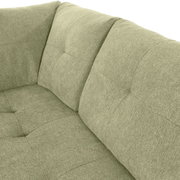 Nahaufnahme einer grünen Sofaecke mit gepolsterten Kissen und texturierter Oberfläche, Perspektive von oben.