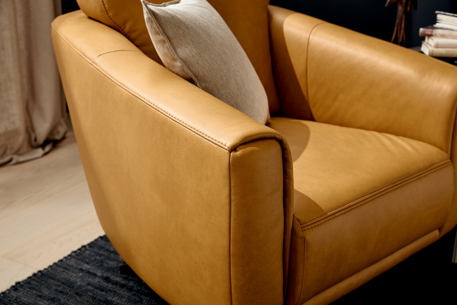 Musterring Drehsessel MR 2490 Nahaufnahme eines eleganten, senffarbenen Ledersessels mit Kissen, seitliche Perspektive