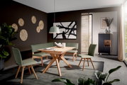 Moderne eethoek met een houten tafel en groene stoelen, een hoekbank en stijlvolle decoratie, gezien vanuit de zijkant.