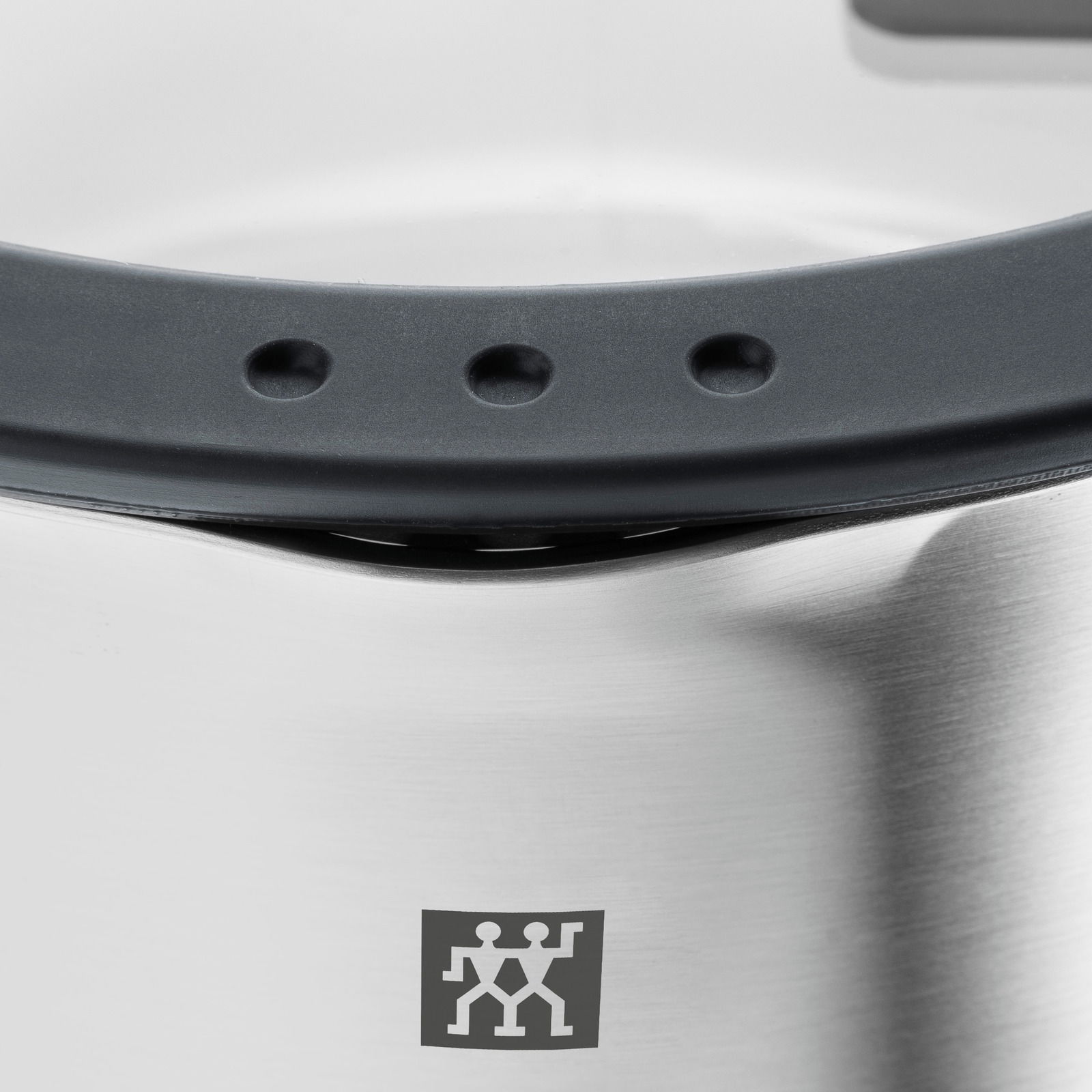 Nahaufnahme eines Edelstahltopfs mit schwarzem Griff und Markenlogo.