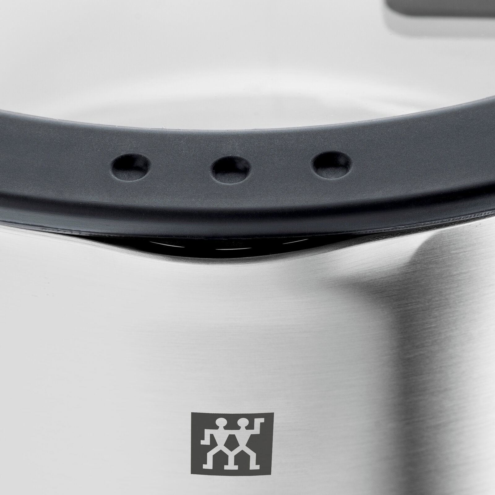 Nahaufnahme eines Edelstahltopfs mit schwarzem Griff und Markenlogo.