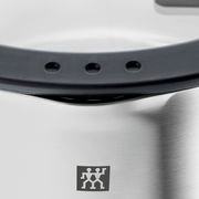 Nahaufnahme eines Edelstahltopfs mit schwarzem Griff und Markenlogo.