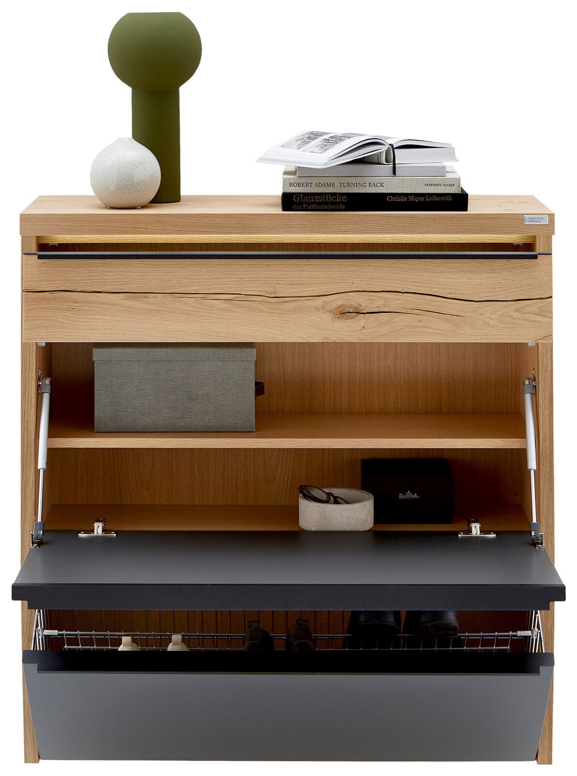 Schuhschrank aus hellem Holz mit geöffneter Klappe in Anthrazit, Innenfächern und Drahtkorb, oben mit Deko und Büchern, Frontansicht.