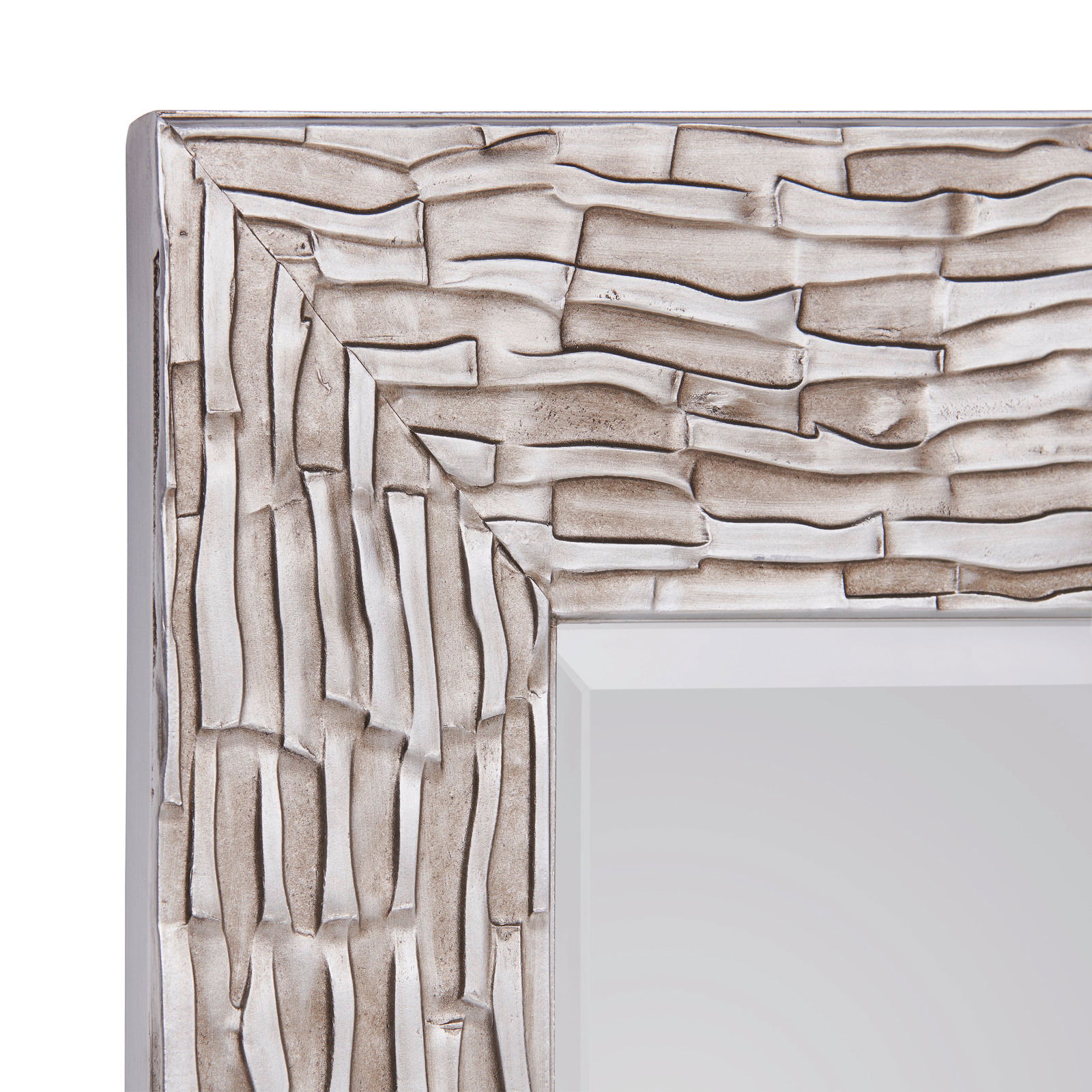 Nahaufnahme eines Spiegels mit strukturiertem, silberfarbenem Rahmen, perspektivisch von der Ecke aus gesehen.