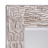 Nahaufnahme eines Spiegels mit strukturiertem, silberfarbenem Rahmen, perspektivisch von der Ecke aus gesehen.