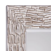 Nahaufnahme eines Spiegels mit strukturiertem, silberfarbenem Rahmen, perspektivisch von der Ecke aus gesehen.