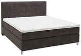 Boxspringbett in seitlicher Perspektive mit dunklem Stoffbezug und weißer Matratze