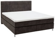 Boxspringbett in seitlicher Perspektive mit dunklem Stoffbezug und weißer Matratze