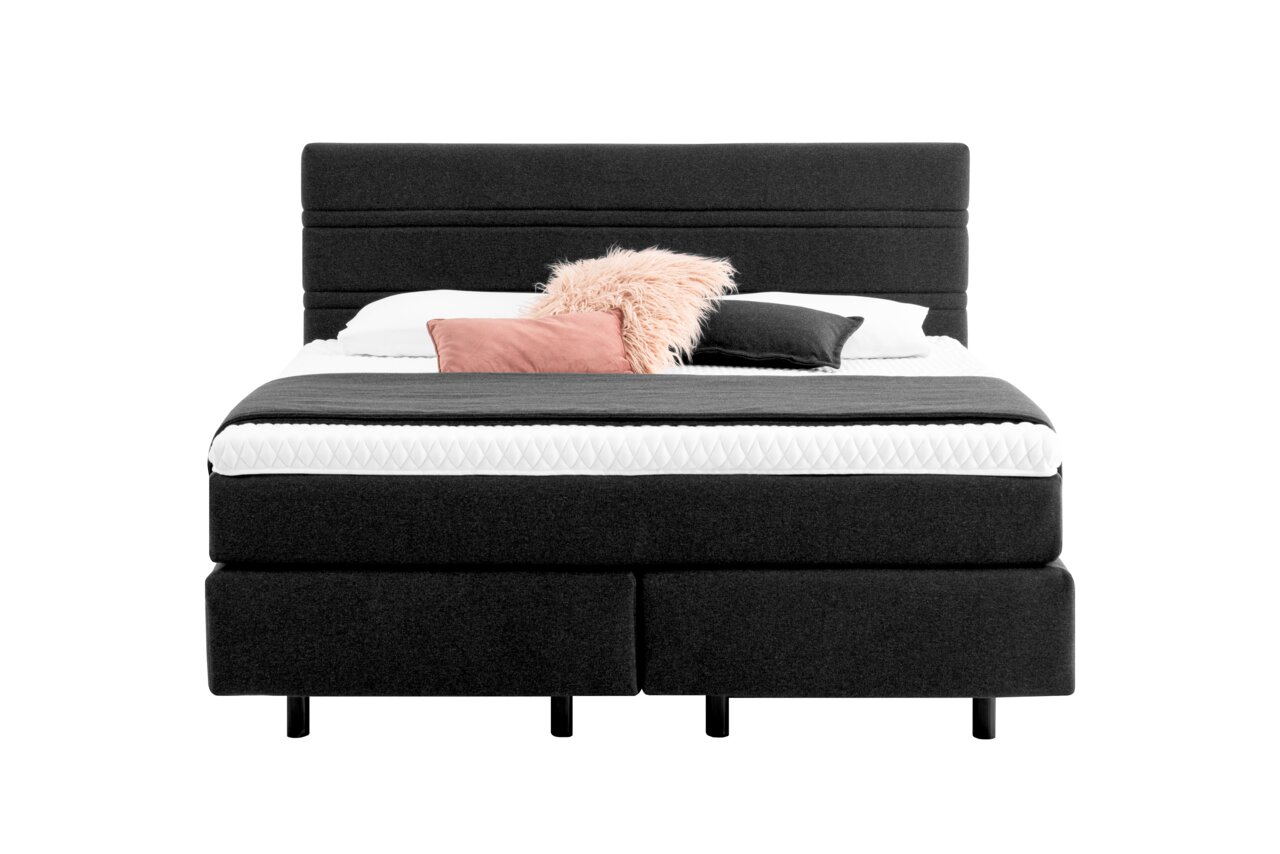 Boxspringbett in dunklem Stoffbezug mit Kopfteil, dekoriert mit Kissen, Frontalansicht