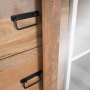 Nahaufnahme einer Vitrine aus Holz mit schwarzen Griffen und einer weißen Seite, seitliche Perspektive.