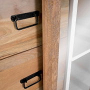 Nahaufnahme einer Vitrine aus Holz mit schwarzen Griffen und einer weißen Seite, seitliche Perspektive.