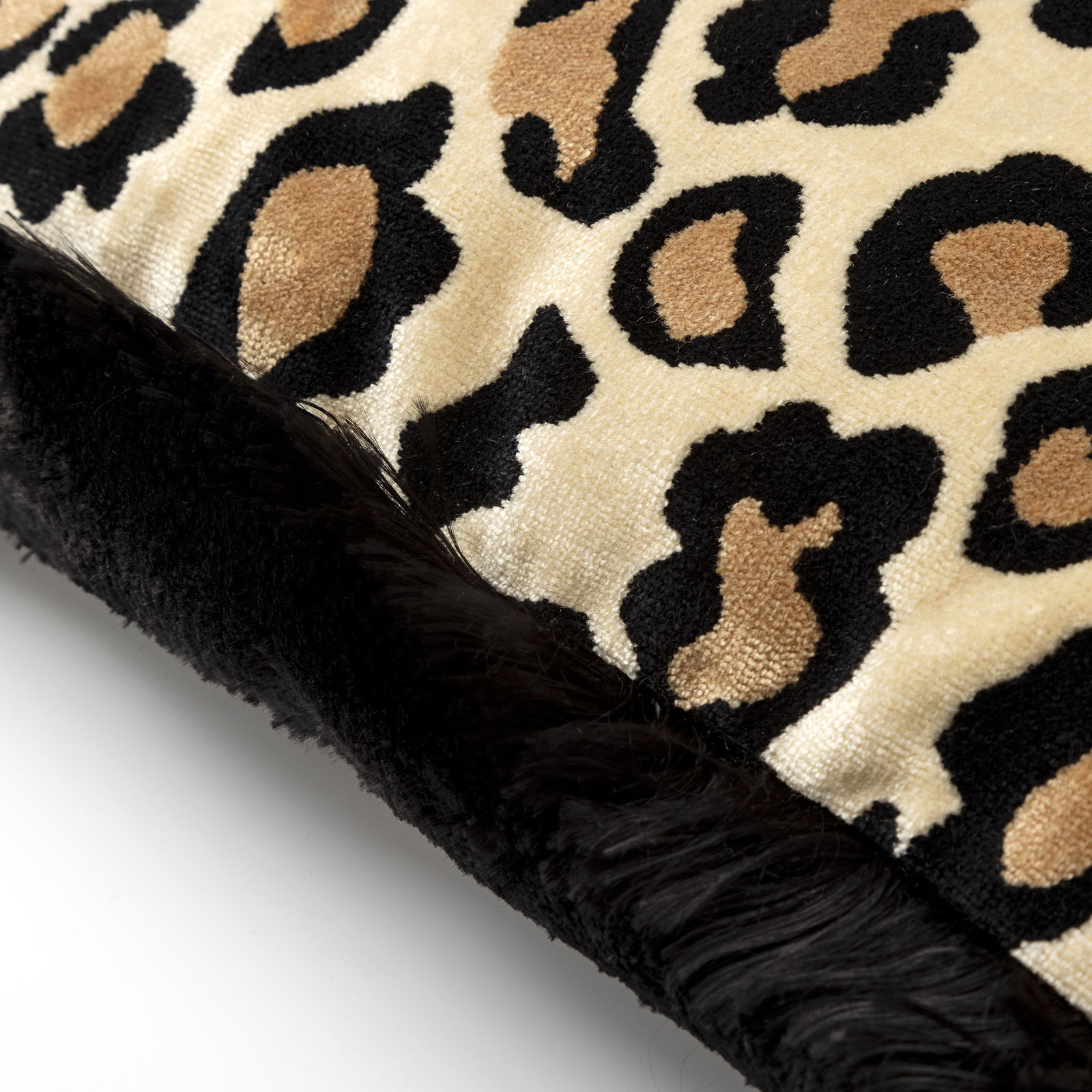 Nahaufnahme eines Dekokissens mit Leopardenmuster und schwarzem Rand.