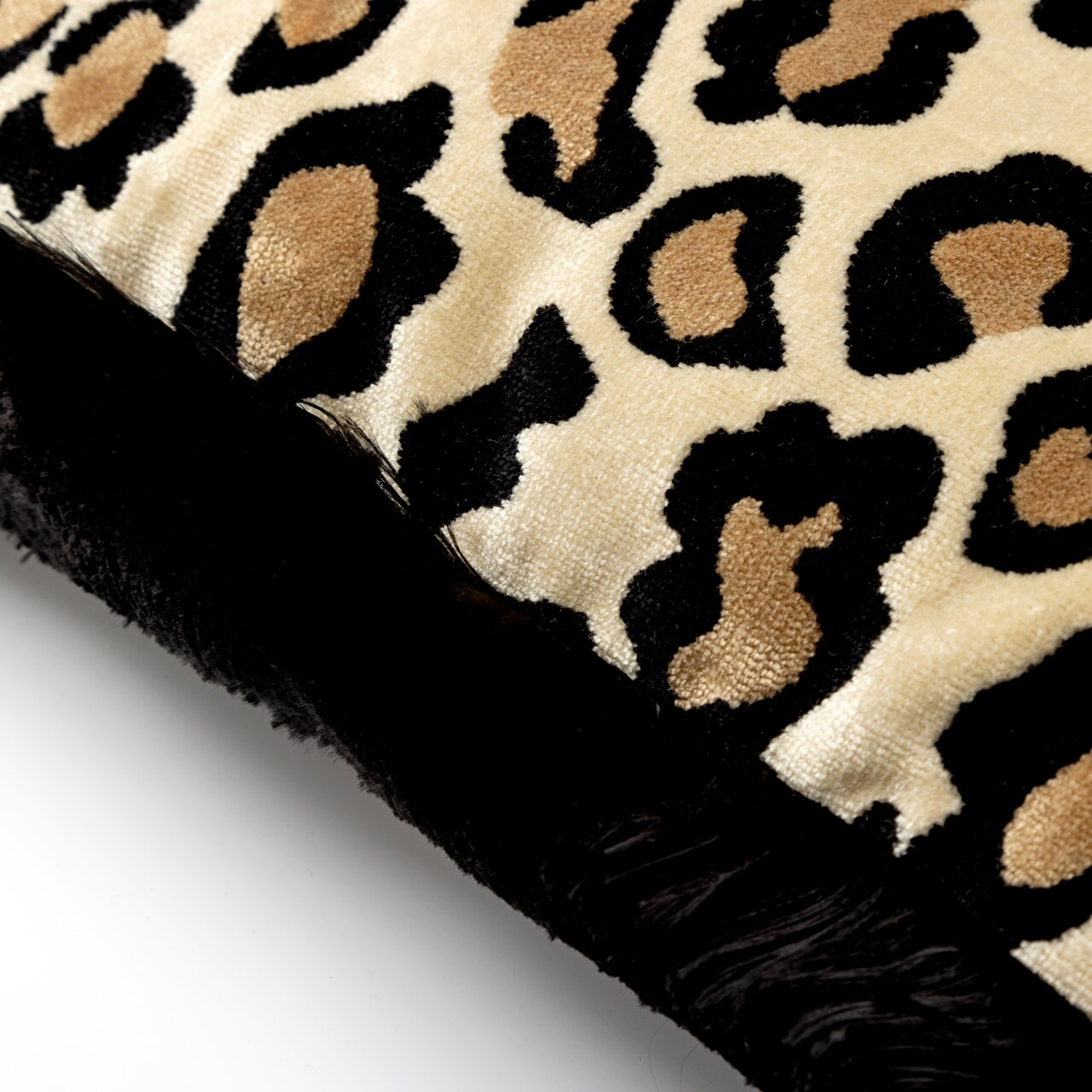 Nahaufnahme eines Dekokissens mit Leopardenmuster und schwarzem Rand.