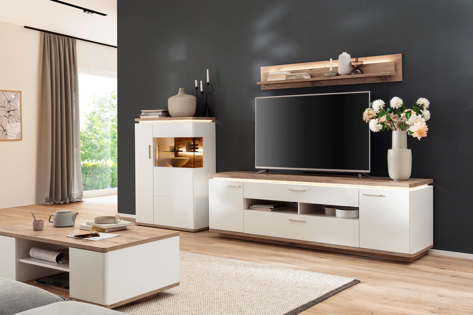 Moderner Couchtisch in hellem Holz und Weiß, im Vordergrund eines stilvoll eingerichteten Wohnzimmers, seitliche Perspektive.