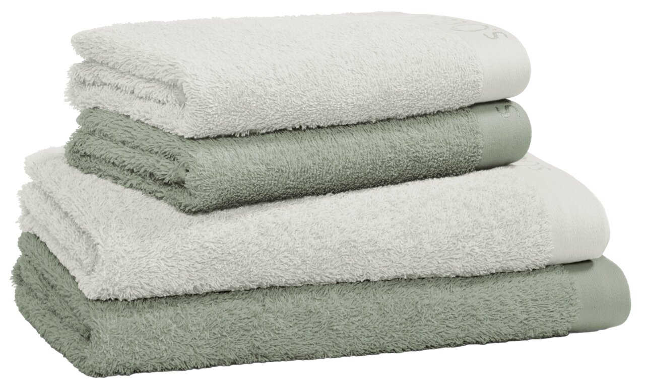 Ein Stapel aus vier Frottierhandtüchern in verschiedenen Grüntönen, seitliche Perspektive.