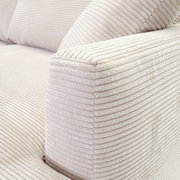 Nahaufnahme einer hellen, gerippten Sofaecke aus Stoff, perspektivisch von der Seite aufgenommen.