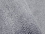 Nahaufnahme eines grauen Wollteppichs mit weicher Textur, schräg fotografiert
