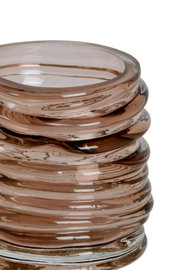 Nahaufnahme eines gestapelten, spiralförmigen Teelichthalters aus braunem Glas mit glänzender Oberfläche.