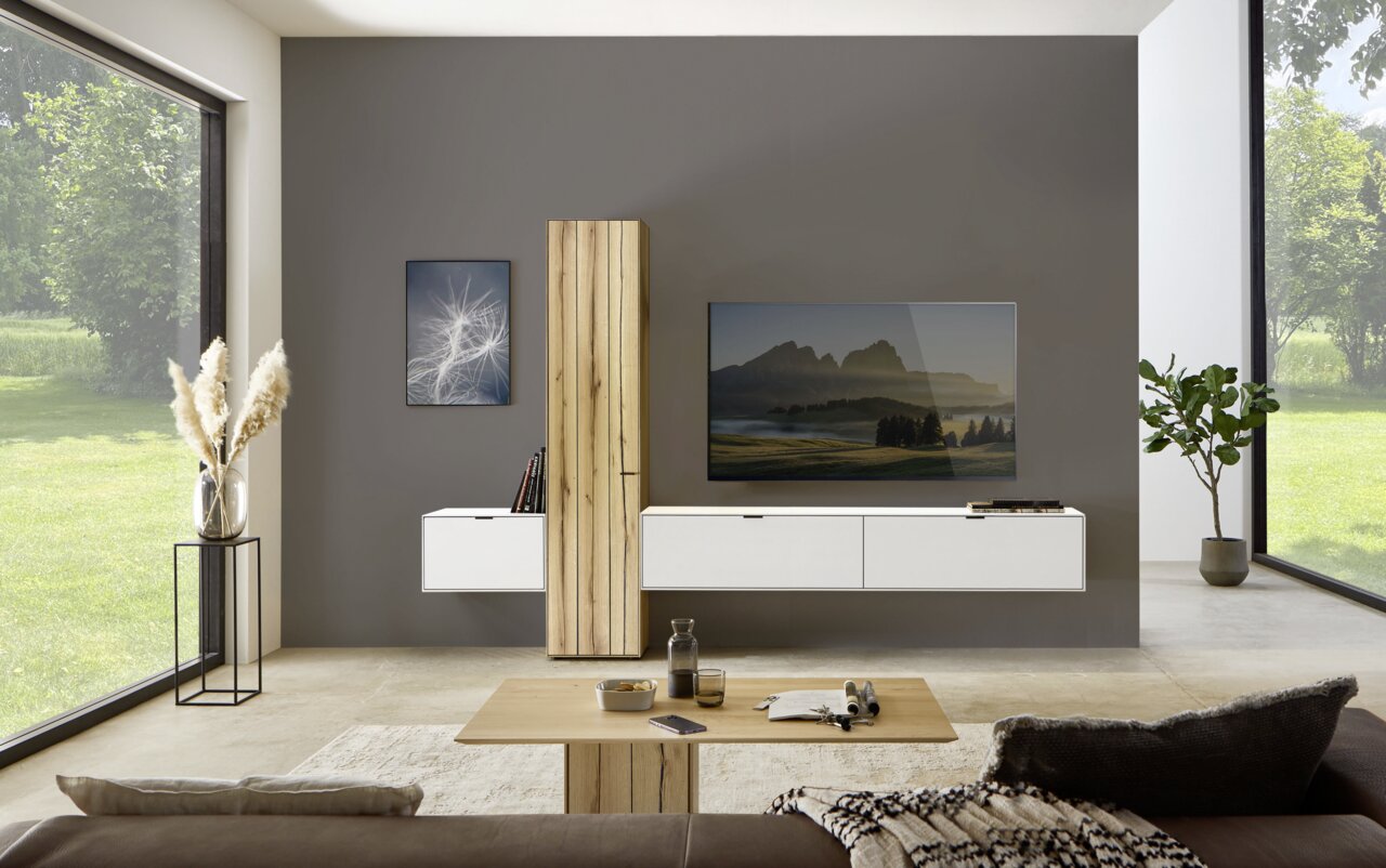 Moderne Wohnzimmerwandkombination mit hölzernem Schrank, weißen Schubladen und einem großen Fernseher, frontal betrachtet.