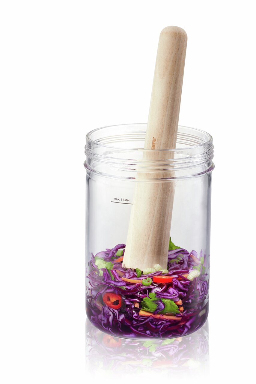 Fermentierset mit Glasbehälter und Holzstampfer, gefüllt mit buntem Gemüse, seitliche Perspektive