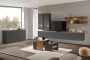 Moderne Wohnzimmermöbel in dunklem Grau mit Holzakzenten, bestehend aus Hängeschränken, TV-Lowboard, Wandregal und Couchtisch, aus seitlicher Perspektive fotografiert.