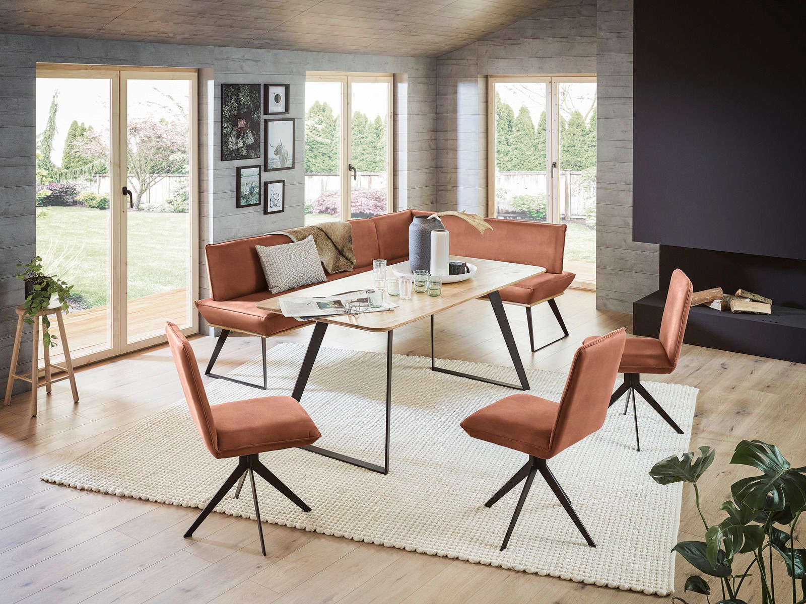 Voleo Hoekbank 243 x 163 cm MALIBU Moderne Eckbank 243x163 cm in einem hellen Wohnzimmer mit großen Fenstern, umgeben von passenden Stühlen und einem Holztisch, aus der Perspektive des Raumes fotografiert.