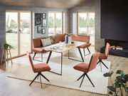 Moderne Eckbank 243x163 cm in einem hellen Wohnzimmer mit großen Fenstern, umgeben von passenden Stühlen und einem Holztisch, aus der Perspektive des Raumes fotografiert.
