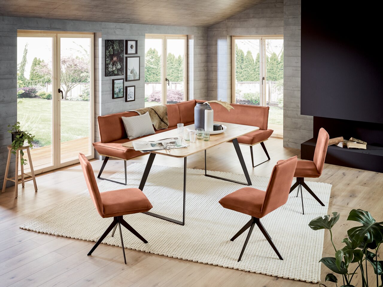 Voleo Eckbank 243x163 cm MALIBU Moderne Eckbank 243x163 cm in einem hellen Wohnzimmer mit großen Fenstern, umgeben von passenden Stühlen und einem Holztisch, aus der Perspektive des Raumes fotografiert.