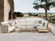 Helle Outdoor-Lounge mit L-förmigem Sofa, Sessel und Couchtisch aus Holz auf moderner Terrasse am Pool mit Meerblick, frontal aus leicht erhöhter Perspektive