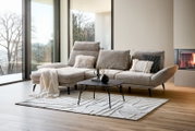 Modernes Longchair-Sofa in einem hellen Wohnzimmer mit großen Fenstern, Blick auf die linke Seite des Sofas.