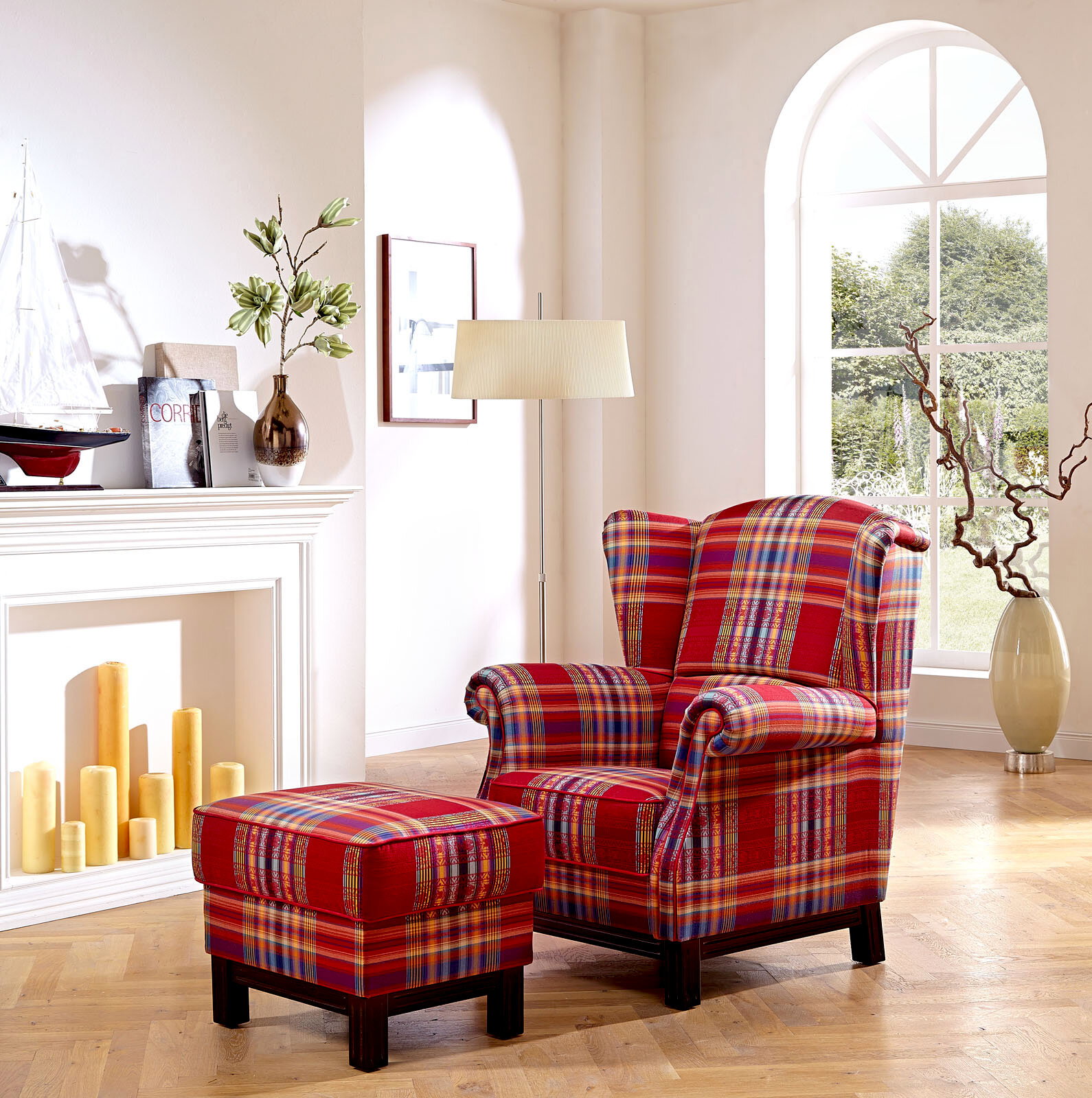Zurbrüggen Solitärsessel OXFORD Karierter Ohrensessel in Rot mit passendem Hocker im hellen Wohnzimmer neben Stehlampe und Kamin, Perspektive: leicht schräg von vorne.